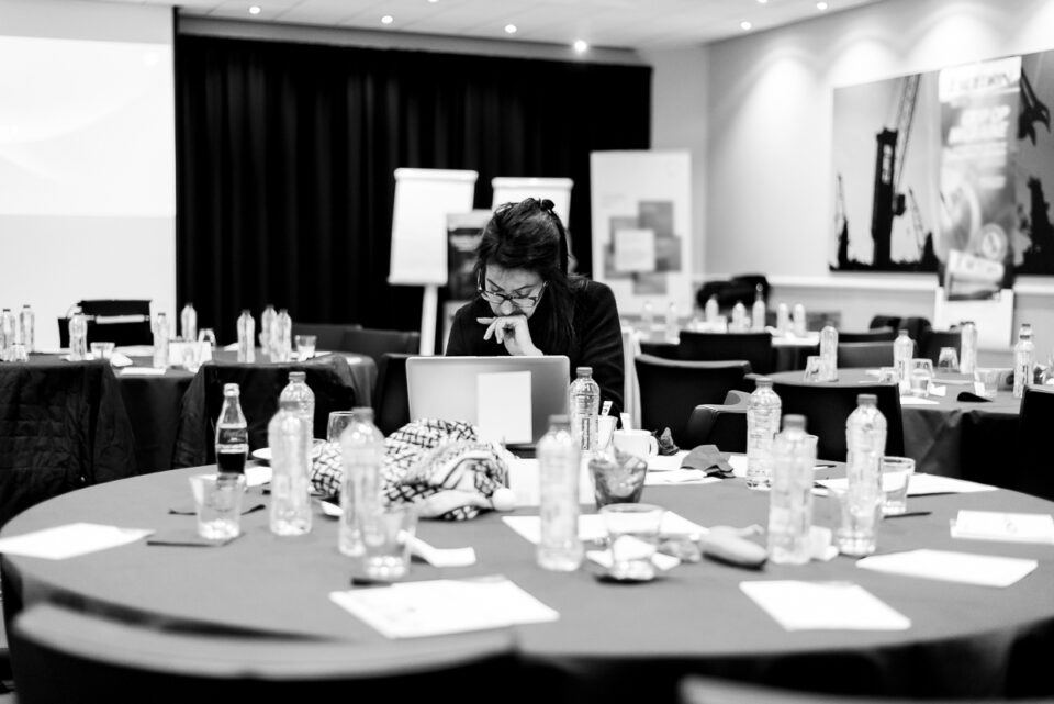 Een werkende dame alleen aan een tafel met laptop tijdens het maken van een evenement reportage. Evenement fotografie, zakelijke fotografie, bedrijfsfotografie, image by Sandra Stokmans Fotografie