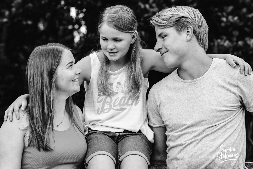 Familie foto van twee zussen en een broer zittend op een hek voor vaderdag, foto door Sandra Stokmans