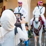 Vrouw maakt foto van kinderen en Qatari paarden met beetje versleten Ipad, reisfotografie Sandra Stokmans Fotografie