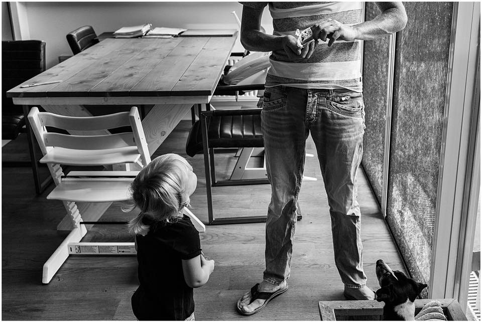 Vader is wat lekkers aan het pakken en kind en hond kijken toe, foto van Christie Agema Fotografie