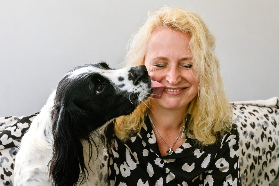 Branding reportage voor de beeldbank van woningcorporatie KleurrijkWonen bij Larisse met haar prachtige springer spaniel Siggy die haar een enthousiaste lik geeft.