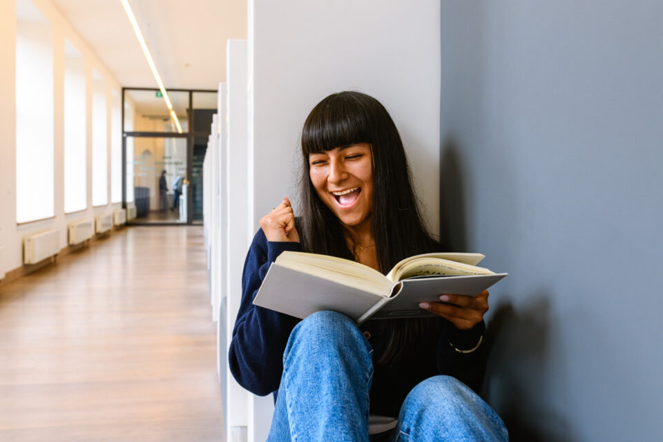 Een spontaan moment van blijdschap terwijl een student in de nis verdiept is in een boek. Deze documentaire-fotografie voegt een vrolijke noot toe aan de universiteit beeldbank en toont de liefde voor leren.