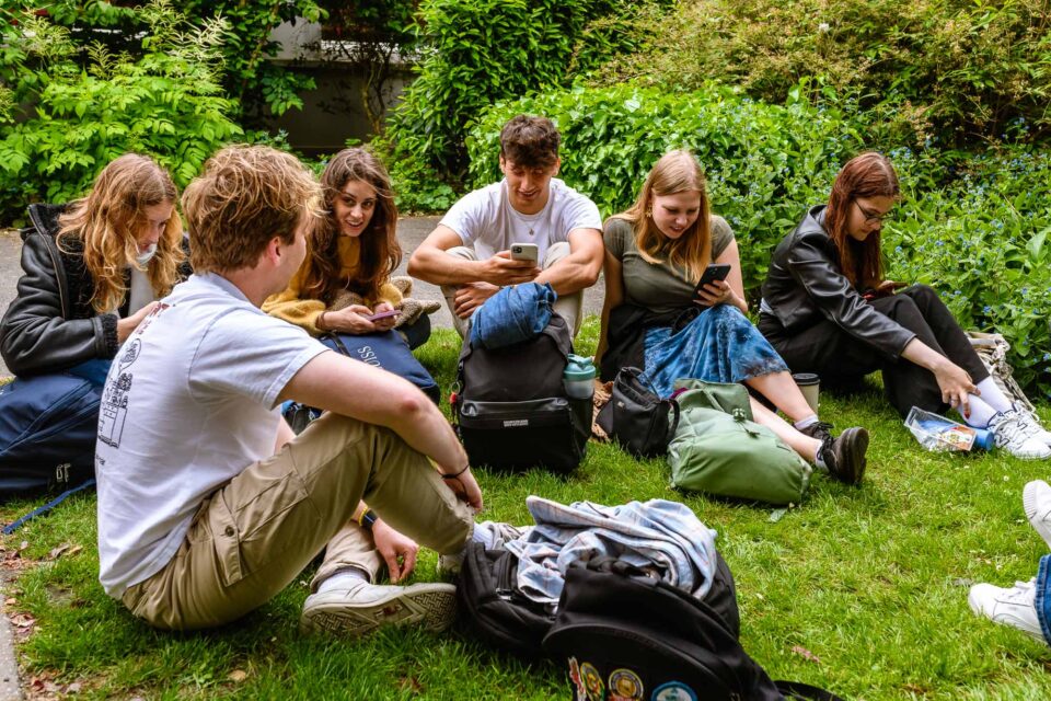 Studenten genieten van hun lunch zittend in het gras, een perfect moment van ontspanning en samenzijn.