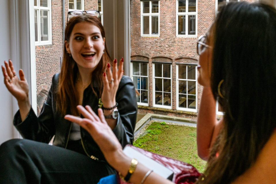 Een spontaan moment tijdens een opdracht aan de Universiteit, vastgelegd in deze documentaire fotoreportage. Op de achtergrond wordt serieus gewerkt, wat de dynamiek van de situatie extra benadrukt.
