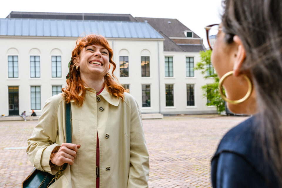 Een lachende medewerker samen met een student op het Janskerkhof in Utrecht