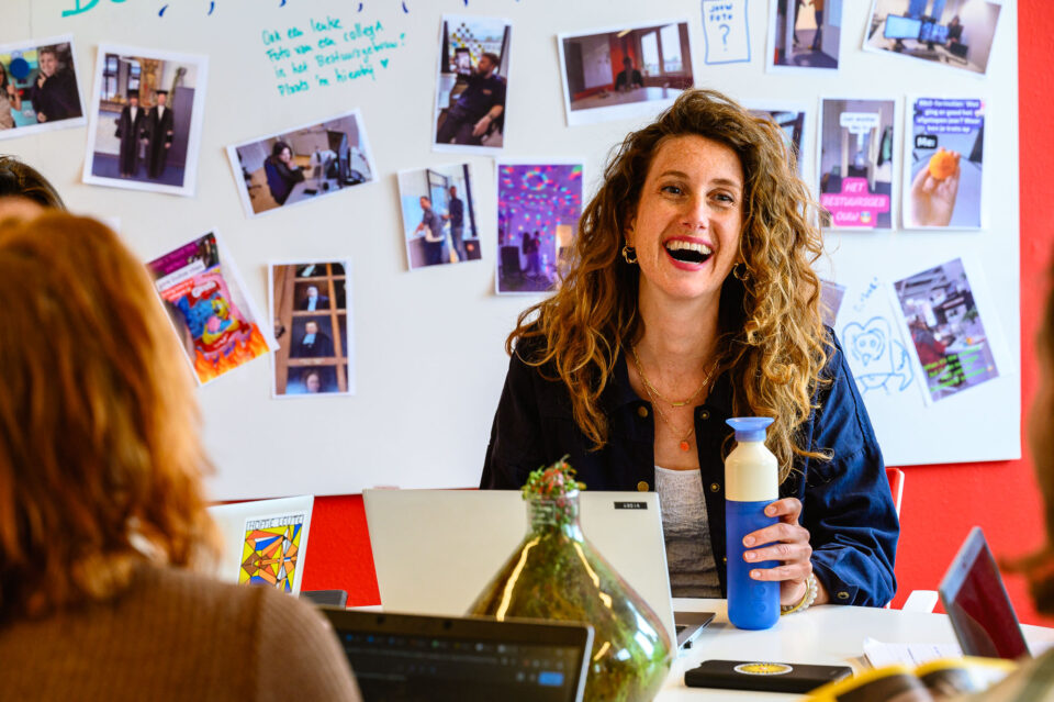 Werkoverleg met lachend portret collega voor de universiteit beeldbank, documentaire fotografie voor onderwijsmarketing